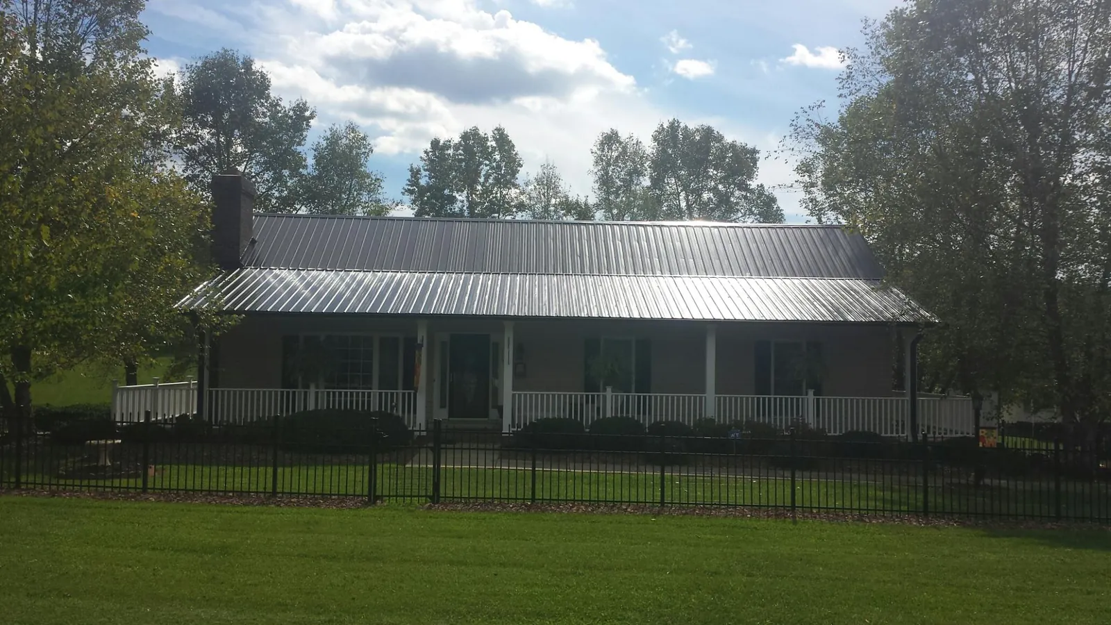 Gray metal roof on a brick ranch with a full width front porch — Gutter Guard Installation work by our crew in Whitmire