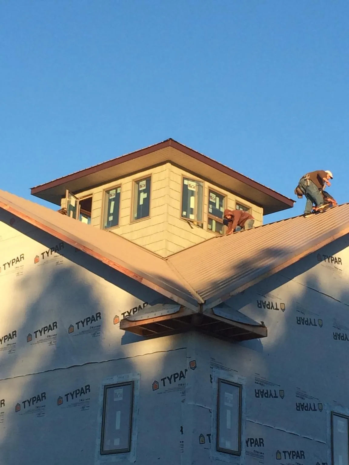 Roofers working around a rooftop cupola on a new metal roof at sunset — Roof Waterproofing in Whitmire by Roofing Brothers